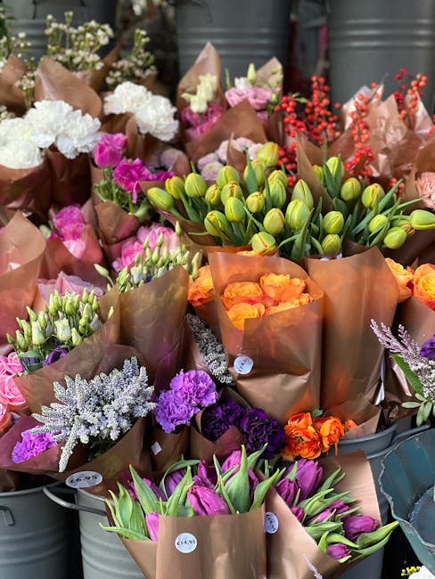 A vibrant display of freshly prepared floral bouquets arranged in metal buckets, featuring a variety of flowers including pink and purple tulips, orange roses, white and purple lilacs, and green tulip